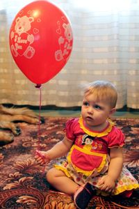 Portrait of cute girl sitting on red balloon