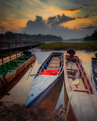 Boats moored in lake against sky during sunset