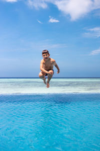 Funny kid jumping into a infinity swimming pool