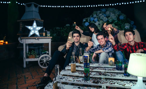 Young friends holding sparkler during party in backyard at night