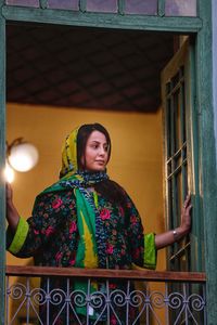 Portrait of young woman with hijab standing against wall