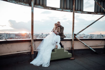 Full length of woman standing by window against sky