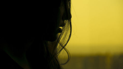 Close-up of silhouette woman against yellow sky