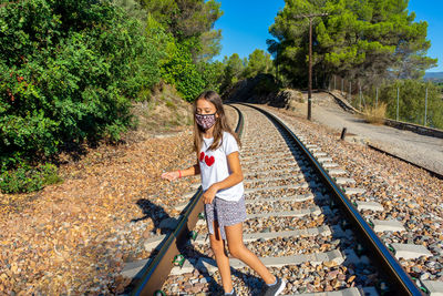 High angle view of cute girl wearing mask standing on railroad track