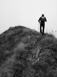 Rear view of man walking on landscape against clear sky