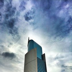 Low angle view of modern building against cloudy sky