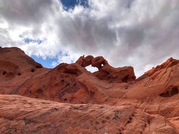 View of rock formations in desert against cloudy sky