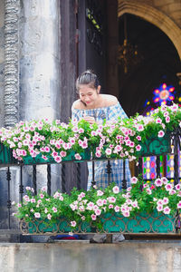 Portrait of woman standing by potted plants