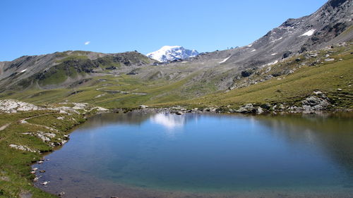 Scenic view of lake and mountains against clear blue sky