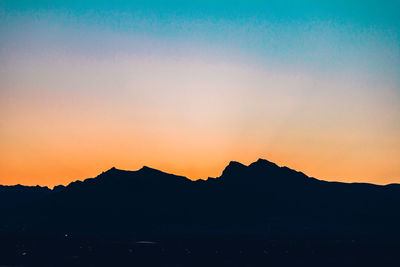 Silhouette mountain against dramatic sky during sunset