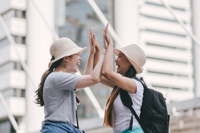 Tourists doing high five while standing in city