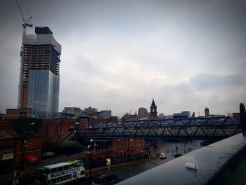 Bridge over river in city against sky