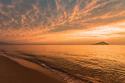 Scenic view of sea against dramatic sky during sunset