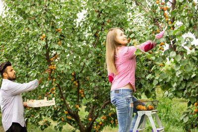 Young woman standing by tree against plants