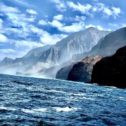 Scenic view of sea by mountains against sky