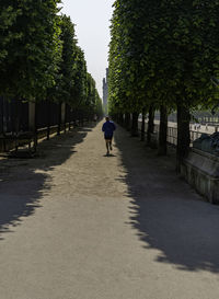 Rear view of man walking on footpath in city