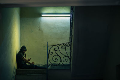 Side view of man sitting by window