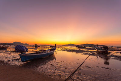 Boats moored on sea against sky during sunset