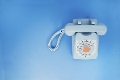 Close-up of telephone booth against blue wall