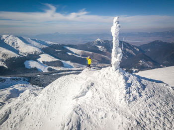 Mid distance view of woman standing on snowcapped mountain