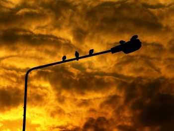 Low angle view of silhouette street light against dramatic sky