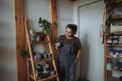 Woman potter holding mugs made by hand from clay