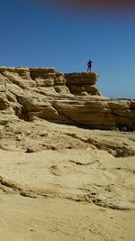 Woman on cliff against clear blue sky