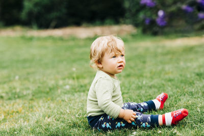 Side view of baby boy sitting on land