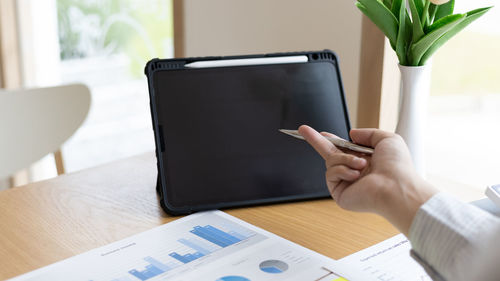 Midsection of man using smart phone on table