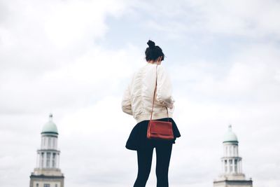 Low angle view of woman against cloudy sky