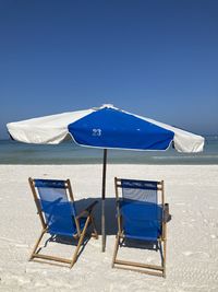 Empty chairs and lounge chair against clear blue sky