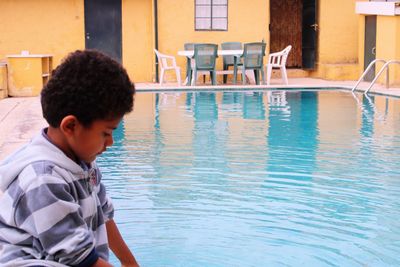 Boy sitting by swimming pool