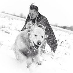 Portrait of young man with dog on snow