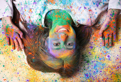 High angle portrait of young woman with face powder lying on floor