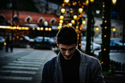 Man standing in illuminated city at dusk