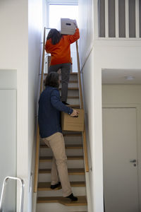 Heterosexual couple with boxes moving up on steps at home