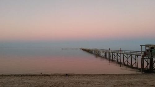 Pier over sea against sky during sunset