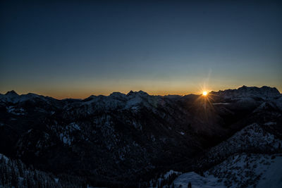 Scenic view of snowcapped mountains against clear sky during sunset