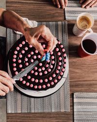 Cropped hands holding candle on cake at table