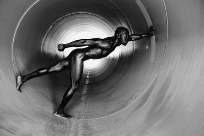 Side view of naked man standing in tunnel
