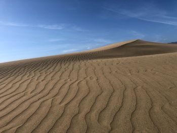 Sand dunes in desert against sky