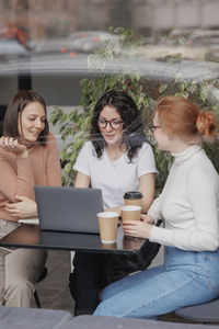 Young woman using laptop while sitting on chair at cafe