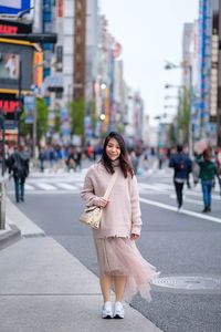 Portrait of woman standing on road in city