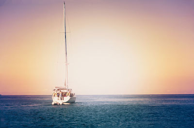 Boat sailing on sea against clear sky during sunset