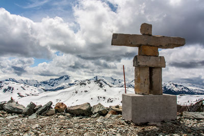 Cross on snow covered mountains against sky