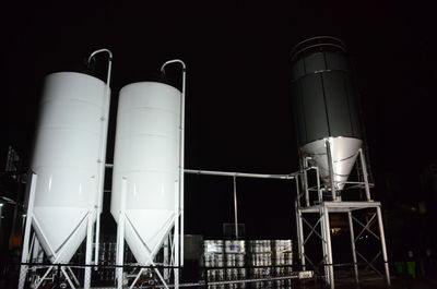 Low angle view of illuminated industry against sky at night