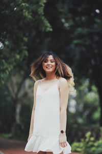 Portrait of smiling woman standing against trees