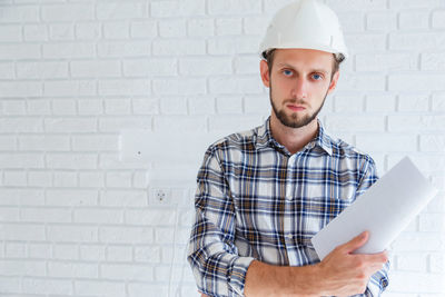 Portrait of young man standing against wall