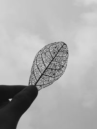 Low angle view of hand holding umbrella against sky