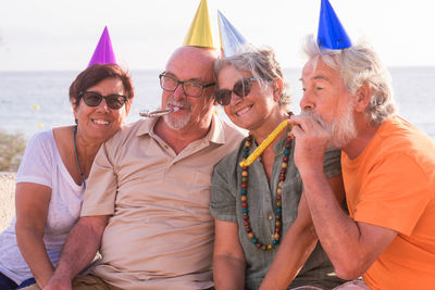 Cheerful senior couples wearing party hat outdoors